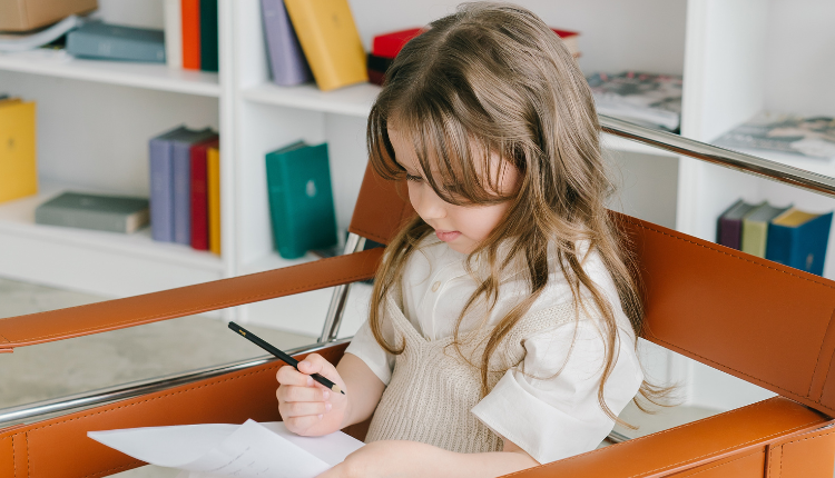 طفلة مصابة باضطراب طيف التوحد تمسك قلماً وورقة للرسم الذي يكون أحد نشاطات معالجة اضطراب التوحد