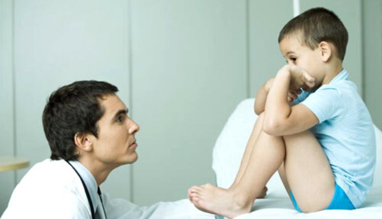 طبيب يجثو في مواجهة طفل محاولا تشخيص اضطراب التوحد