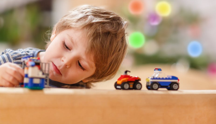 طفل صغير مصاب باضطراب طيف التوحد من المستوى الثالث يلعب بألعاب السيارات لوحده 